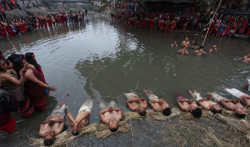Nepalese Hindu devotees offer prayers before taking holy dips at Hanumante River during Madhav Narayan festival in Bhaktapur, Nepal. Nepalese Hindu women observe a fast and pray Goddess Swasthani and God Madhav Narayan for longevity of their husbands and family prosperity during the month-long festival. Image by Sunil Sharma. Used with permission.