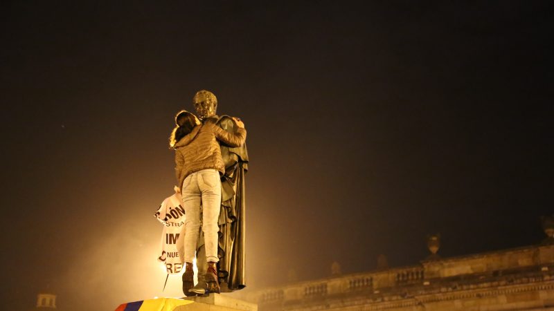 Una manifestante subiendo a la estatua de Simón Bolívar, héroe nacional de Colombia. Foto por Ana Luisa González, utilizada con autorización. 