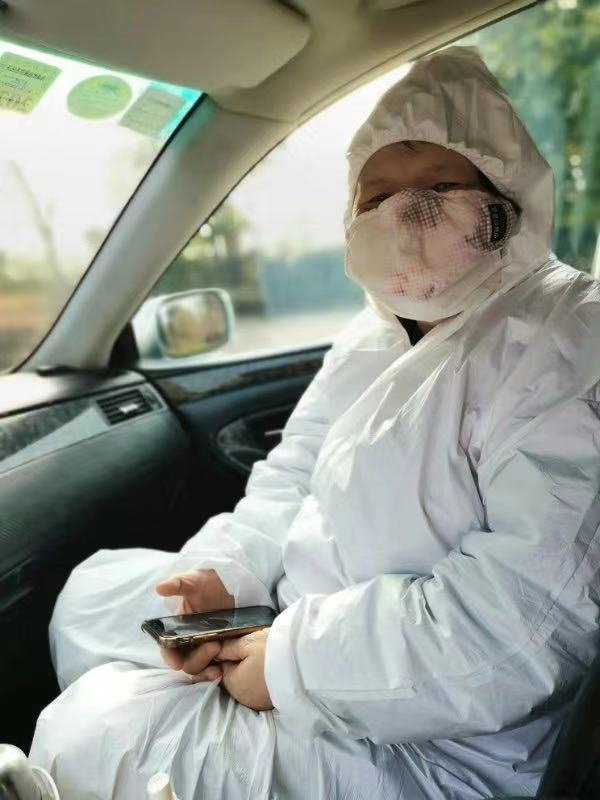 Ai Xiaoming dans une voiture, vêtue de la tête aux pieds d'une combinaison.