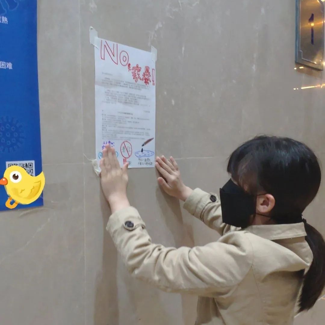 Une jeune fille portant un masque de protection faciale accroche une affiche sur un mur.