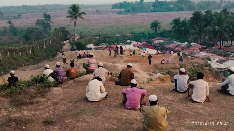 Des réfugiés rohingya se tiennent assis sur un talus, maintenant les distances sanitaires en période pandémie de COVID-19.