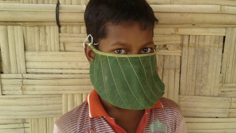Un jeune garçon porte un masque de protection faciale fabriqué à partir d'une grande feuille.