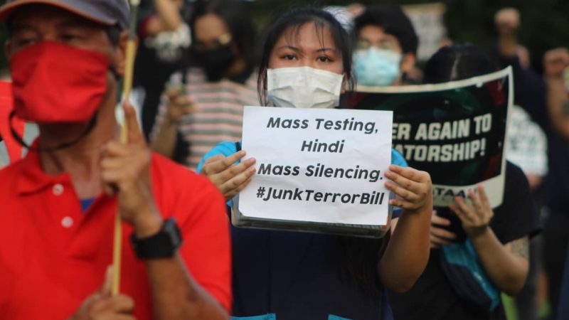 Gros plan sur des manifestants aux Philippines, qui protestent contre la loi anti-terroriste en brandissant des pancartes.