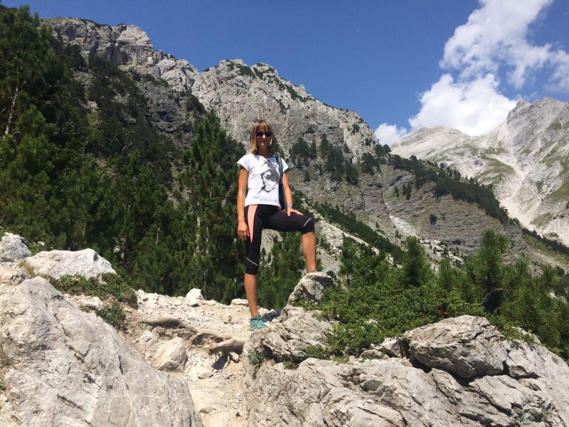 La blogueuse de voyage polonaise Justyna Mleczak en tenue athlétique, juchée sur un rocher devant un paysage montagneux.