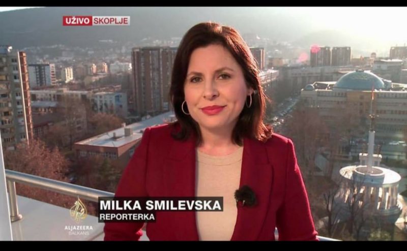La journaliste Milka Smilevska s'exprime sur la chaîne Al Jazeera, avec la ville de Skopje en arrière-plan.