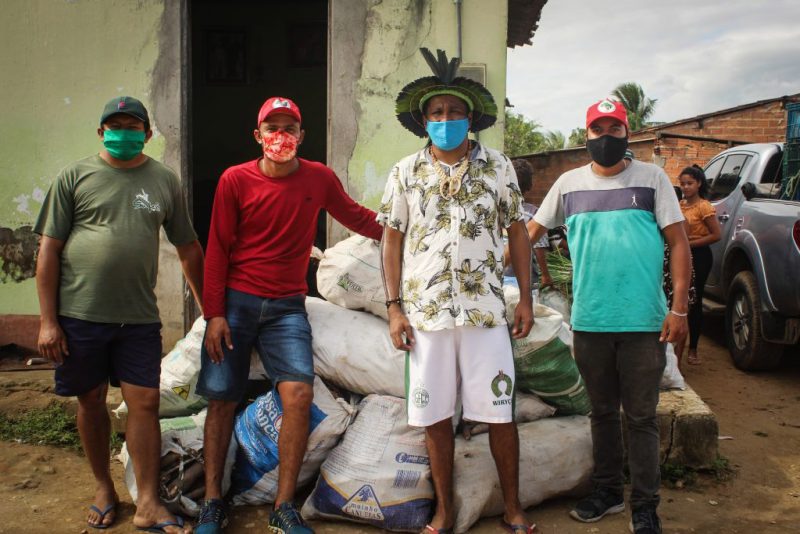 Quatre agriculteurs brésiliens posent avec leurs masques de protection faciale devant les sacs de nourriture qu'ils vont distribuer aux populations indigènes.