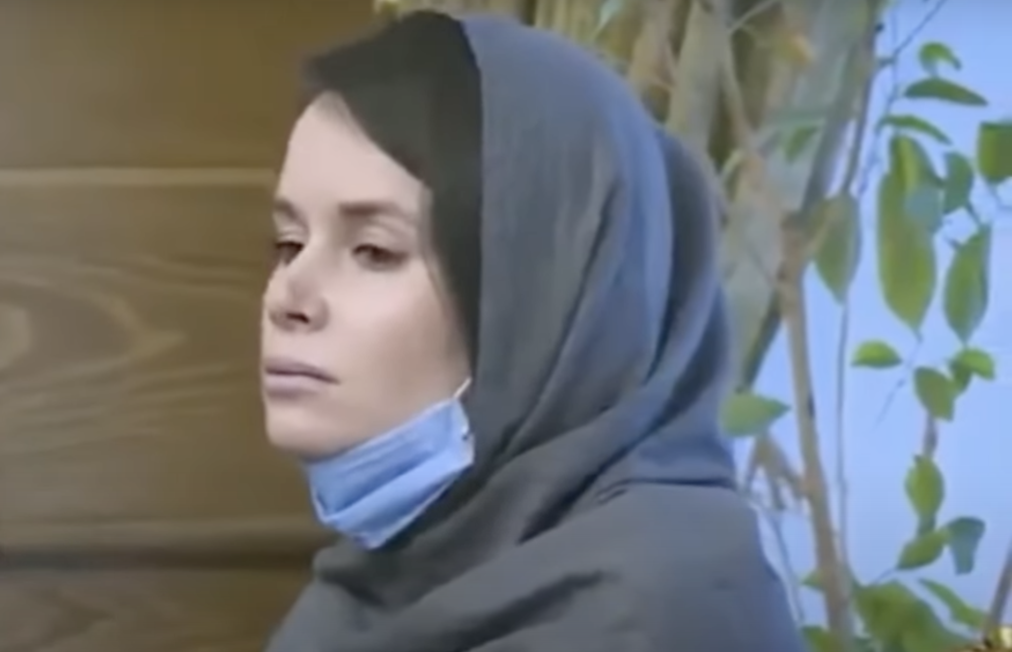 Kylie Moore-Gilbert, de profil, dans une tenue islamique qui lui couvre la tête, laissant visibles des cheveux noirs sur le haut du front. Elle porte le regard par terre et son visage est plutôt triste.