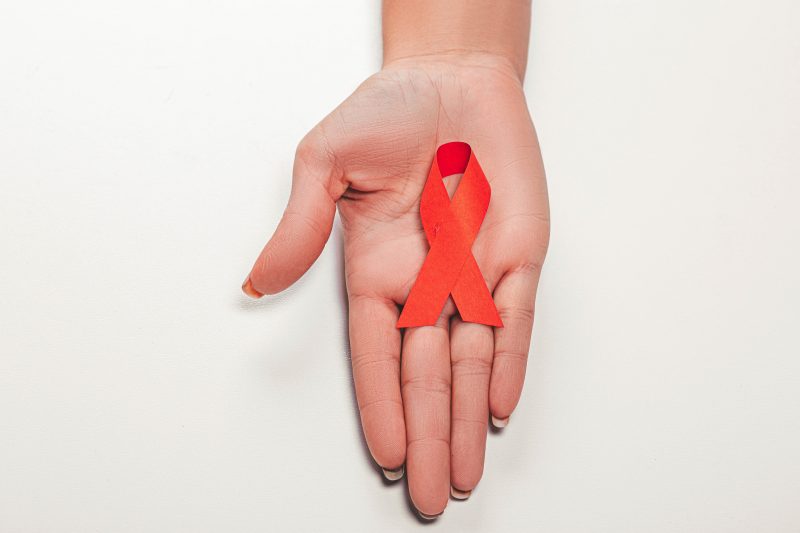 Main de femme avec un ruban rouge qui symbolise la lutte contre le SIDA.