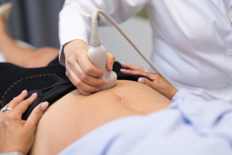 Le ventre d'une femme enceinte est examiné à l'aide d'une sonde pour une échographie.