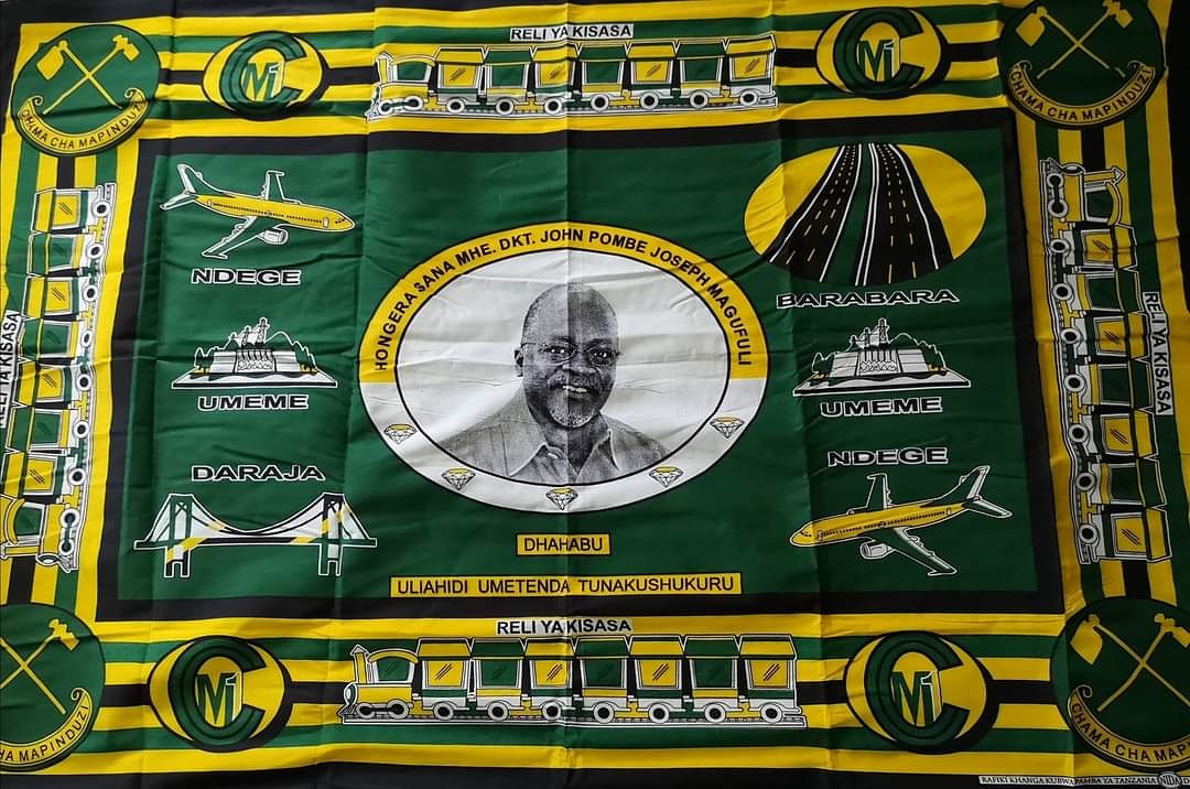 Un pagne vert et jaune, les couleurs du CCM, représente John Magufuli au centre, entouré des symboles de ses réformes.