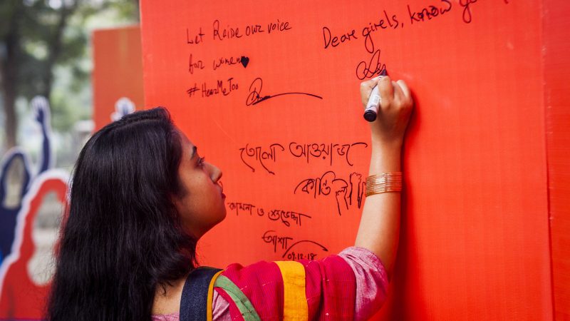 A Rajshahi University student signs a pledge prevent violence against women in Dhaka, Bangladesh. Image by UN Women via Flickr. CC BY-NC-ND