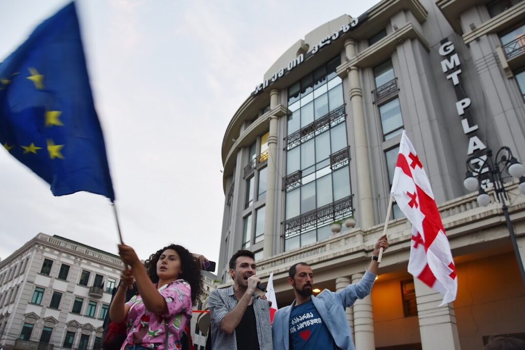 نشطاء يلوحون بعلميّ جورجيا و الاتحاد الأوروبي بمظاهرة في تبليسي. صورة: OC Media. استخدمت بتصريح.