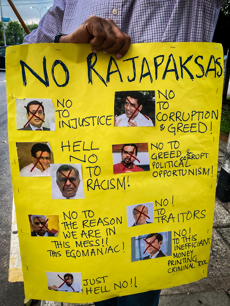 A protester holds up a poster condemning Sri Lanka's corrupt political culture. The poster features not just members of the ruling party but also members of the opposition.