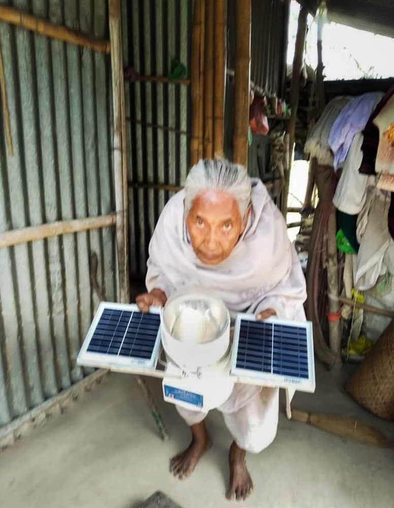 98 year old Usha Rani Das from the remote Bikrampur village of Tripura flaunts a micro solar dome that brought a sea of change to her life. Image credit: NBIRT. Used with permission.