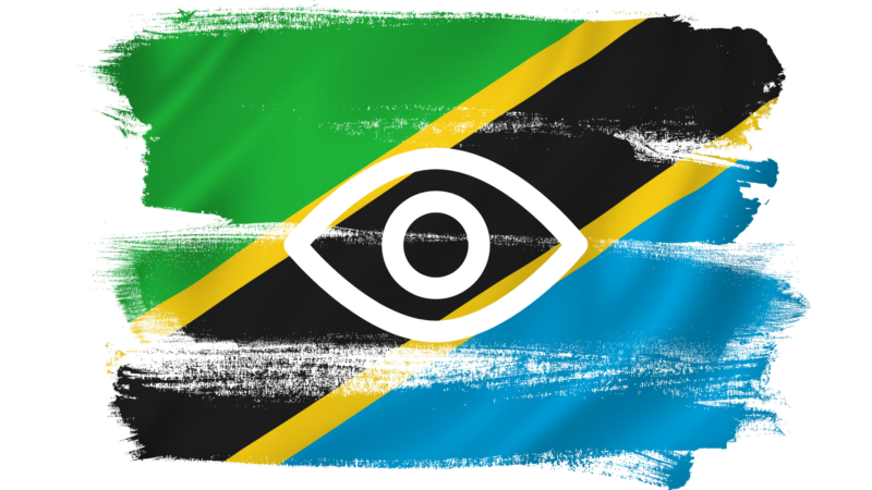 The Tanzanian flag (a digonal blak stripe bordered in yellow separates a green upper traingle from a blue lower one) is painted on a white background with a simple illustration of an eye in white superimposed upon it