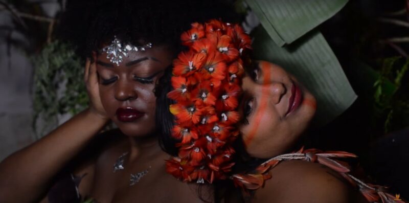 Une femme Noire et une femme autochtone posent avec un bijou de tête en strass et une couronne de fleurs