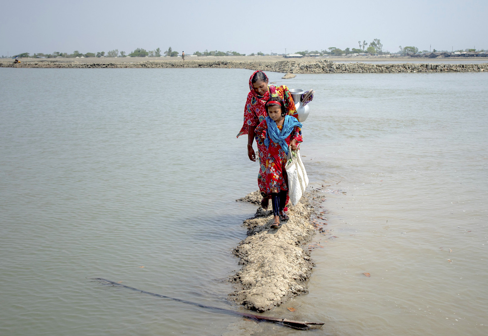 Une femme et une fille marchant au milieu de la rivière avec une cruche dans les bras
