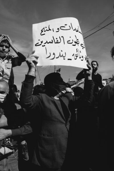مُحتج يرفع لافتّة تقول، "المساعدات والمنح في بطون الفاسدين".