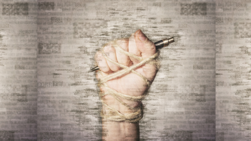 A restrained hand holding a pen