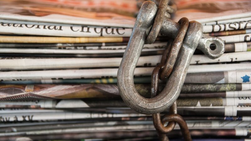 A stack of newspapers is chained and locked with a padlock