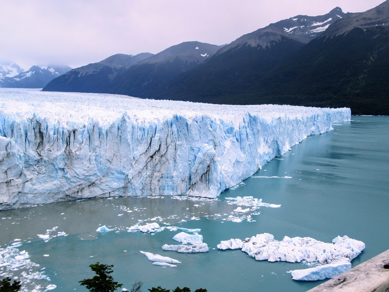 Paysage représentant un glacier au bord d'un lac et au pied des montagnes.